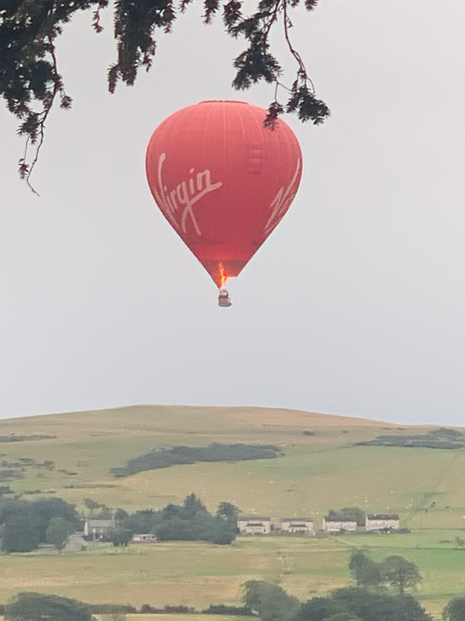 Hot air balloon floating above the Medwin valley with farm buildings and hills in the background
